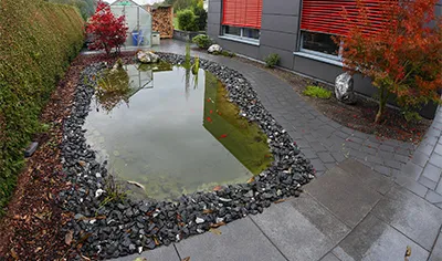 Angelegter Gartenteich mit Kiesrand direkt am Haus